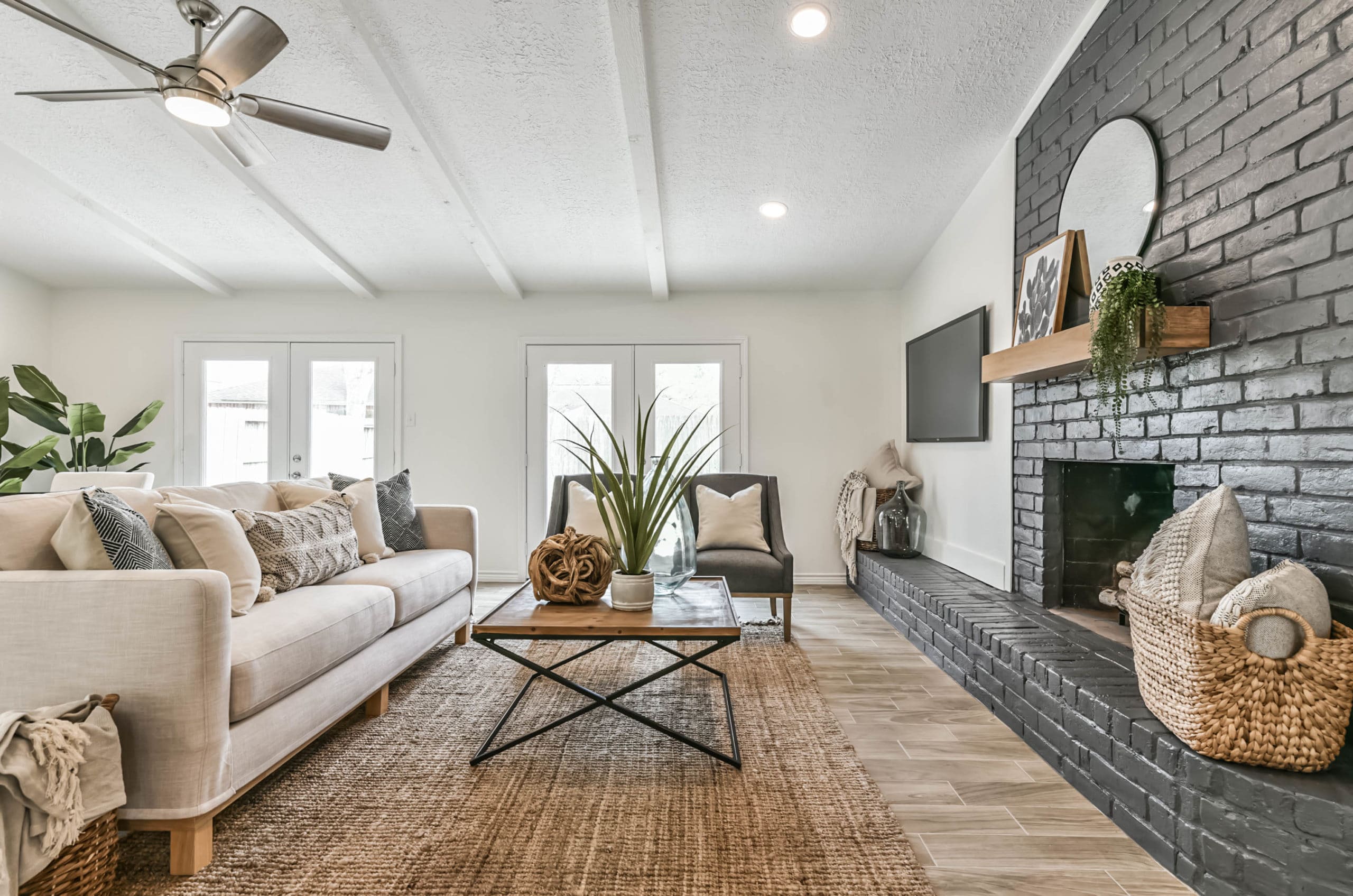 A home staging example of a living space with a couch and coffee table facing a brick fireplace.