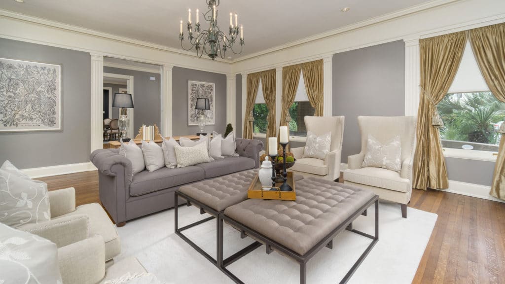 Beautiful example of home staging. A luxurious living room with gold curtains, couch, chairs and coffee table.